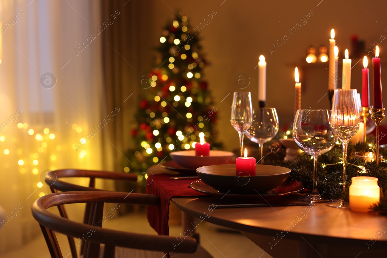 Photo of Festive table setting in room decorated for Christmas, closeup. Bokeh effect