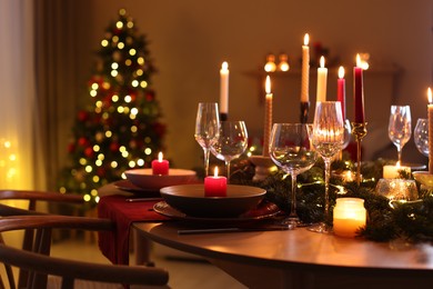 Photo of Festive table setting in room decorated for Christmas, closeup. Bokeh effect