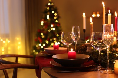 Photo of Festive table setting in room decorated for Christmas, closeup. Bokeh effect