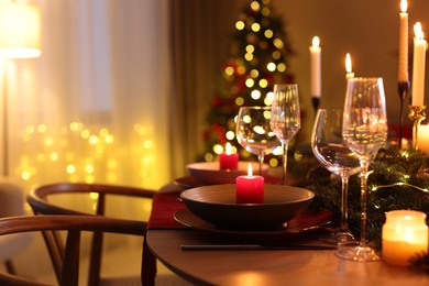 Photo of Festive table setting in room decorated for Christmas, closeup. Bokeh effect