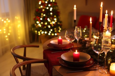 Photo of Festive table setting in room decorated for Christmas, closeup. Bokeh effect