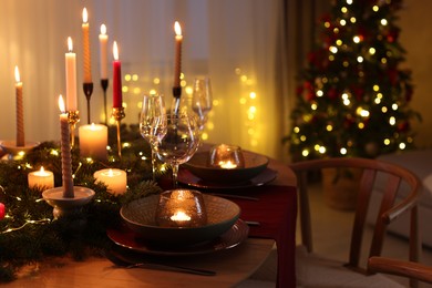 Photo of Festive table setting in room decorated for Christmas. Bokeh effect