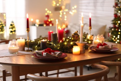 Photo of Festive table setting in room decorated for Christmas, closeup. Bokeh effect