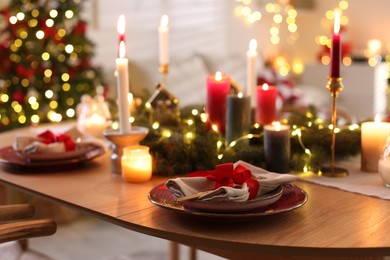 Photo of Festive table setting in room decorated for Christmas, closeup. Bokeh effect