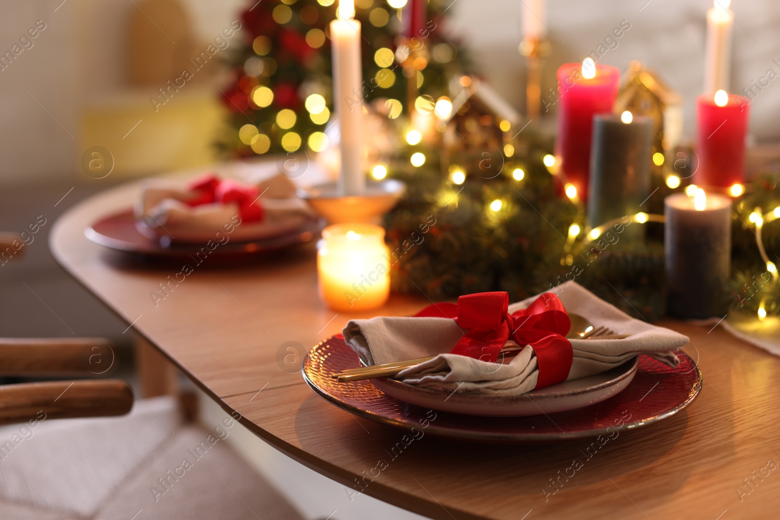 Photo of Festive table setting in room decorated for Christmas, closeup. Bokeh effect