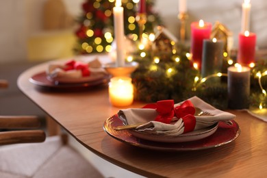 Photo of Festive table setting in room decorated for Christmas, closeup. Bokeh effect