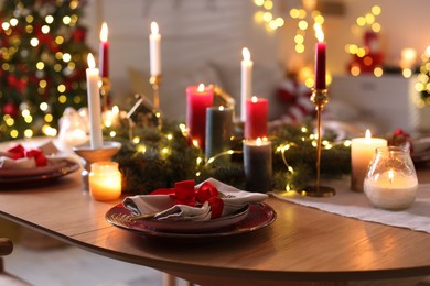 Photo of Festive table setting in room decorated for Christmas, closeup. Bokeh effect