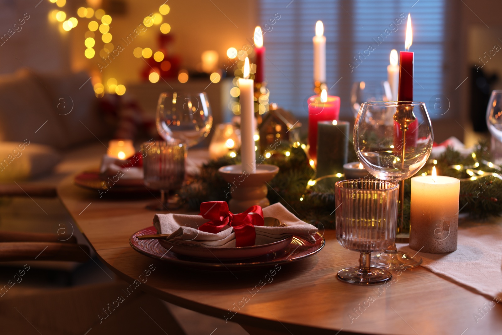 Photo of Festive table setting in room decorated for Christmas, closeup. Bokeh effect