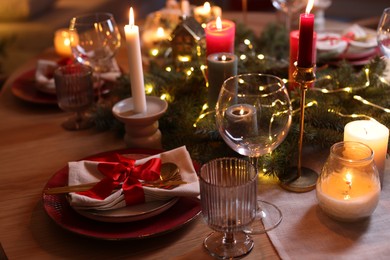 Photo of Festive table setting in room decorated for Christmas, closeup. Bokeh effect