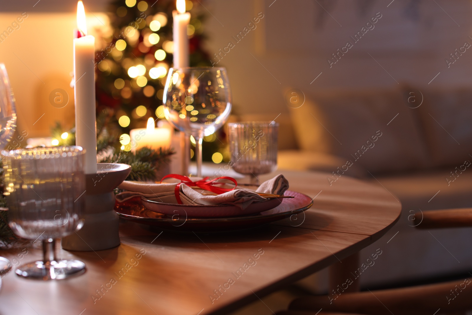 Photo of Festive table setting in room decorated for Christmas, closeup. Bokeh effect