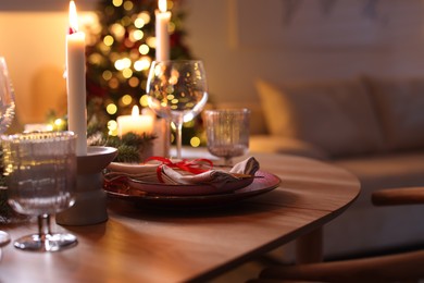 Photo of Festive table setting in room decorated for Christmas, closeup. Bokeh effect