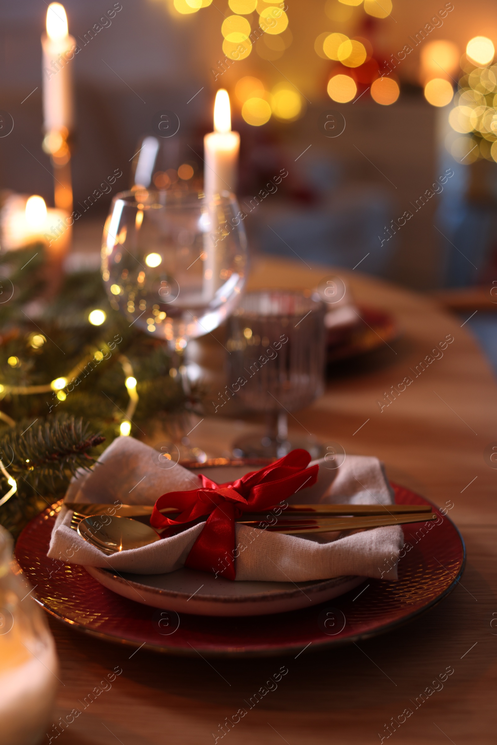 Photo of Festive table setting in room decorated for Christmas, closeup. Bokeh effect