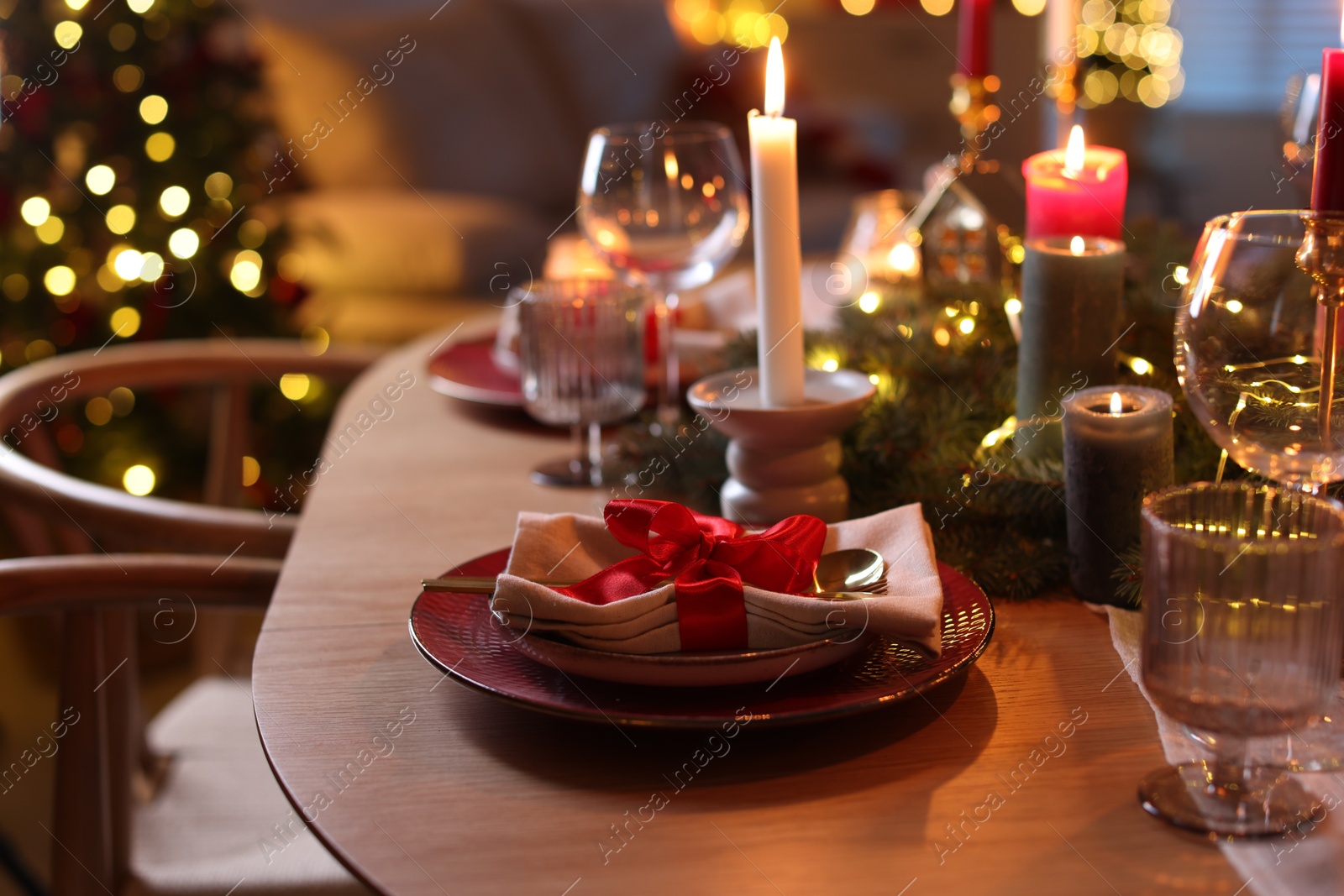 Photo of Beautiful dishware and Christmas lights on wooden table indoors, closeup