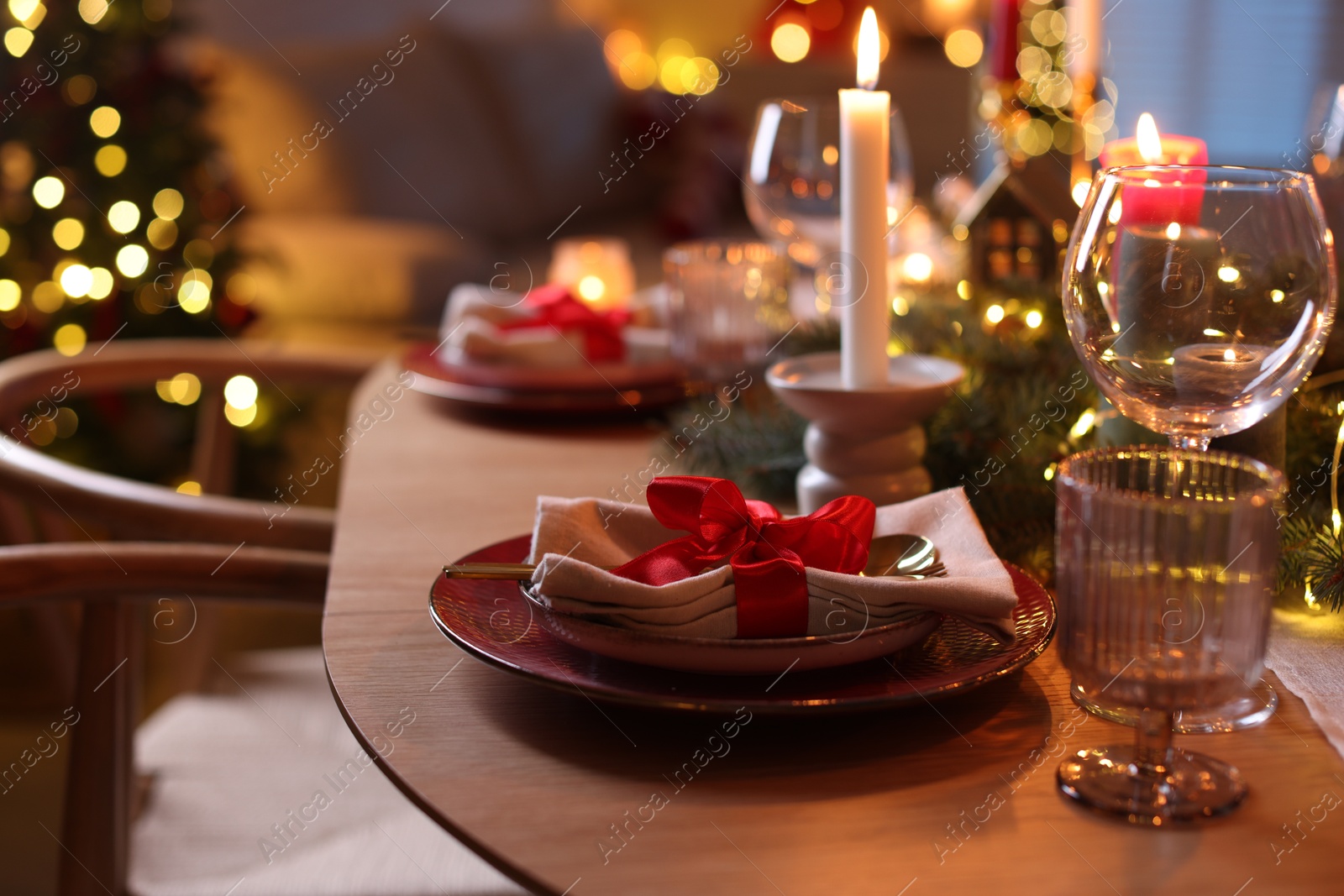 Photo of Beautiful dishware and Christmas lights on wooden table indoors, closeup