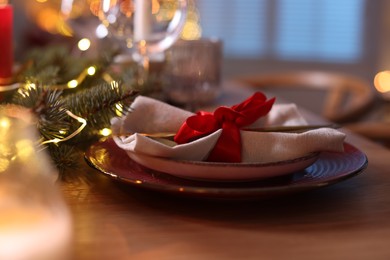 Photo of Beautiful dishware and Christmas lights on wooden table indoors, closeup