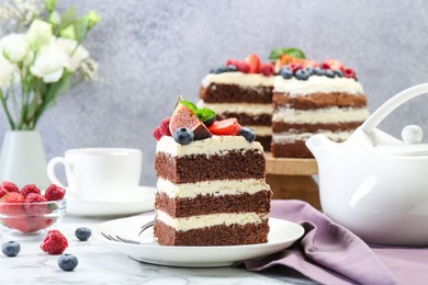 Photo of Piece of delicious chocolate sponge cake with berries served on white table