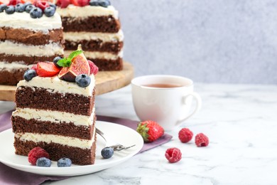 Photo of Piece of delicious chocolate sponge cake with berries served on white table