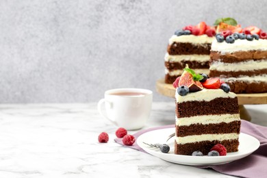 Photo of Piece of delicious chocolate sponge cake with berries served on white table. Space for text