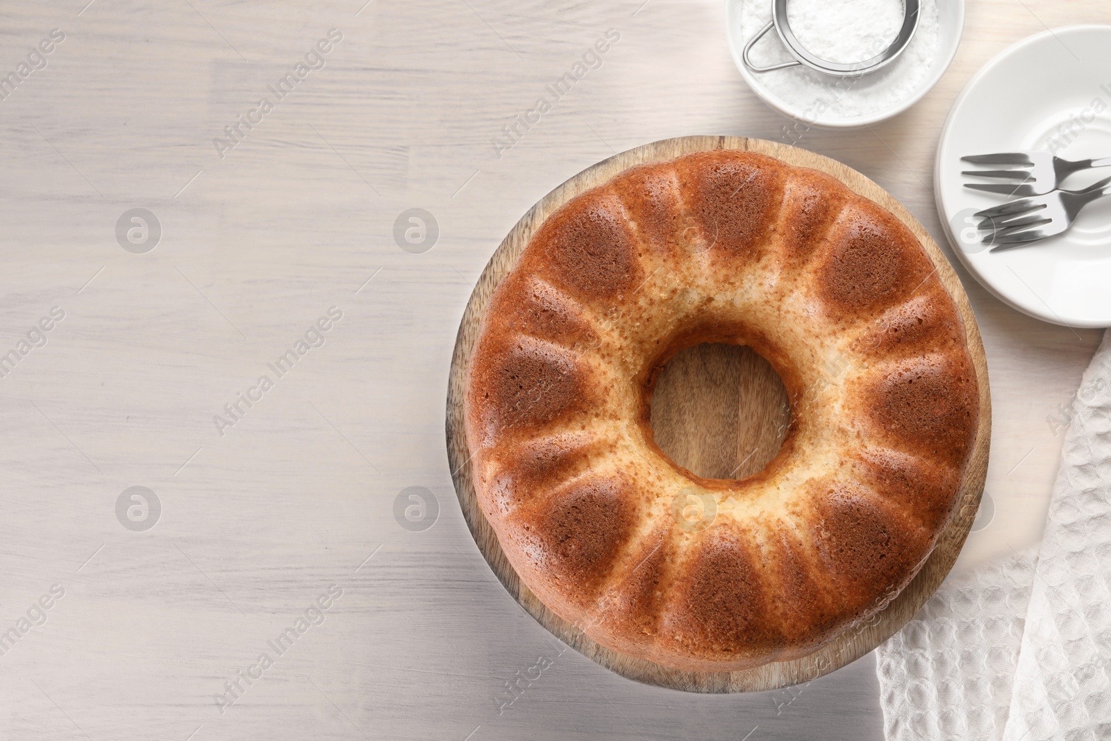 Photo of Freshly baked sponge cake served on white wooden table, top view. Space for text