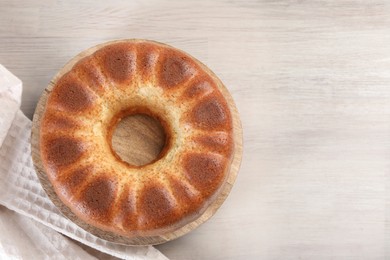 Photo of Freshly baked sponge cake on white wooden table, top view. Space for text