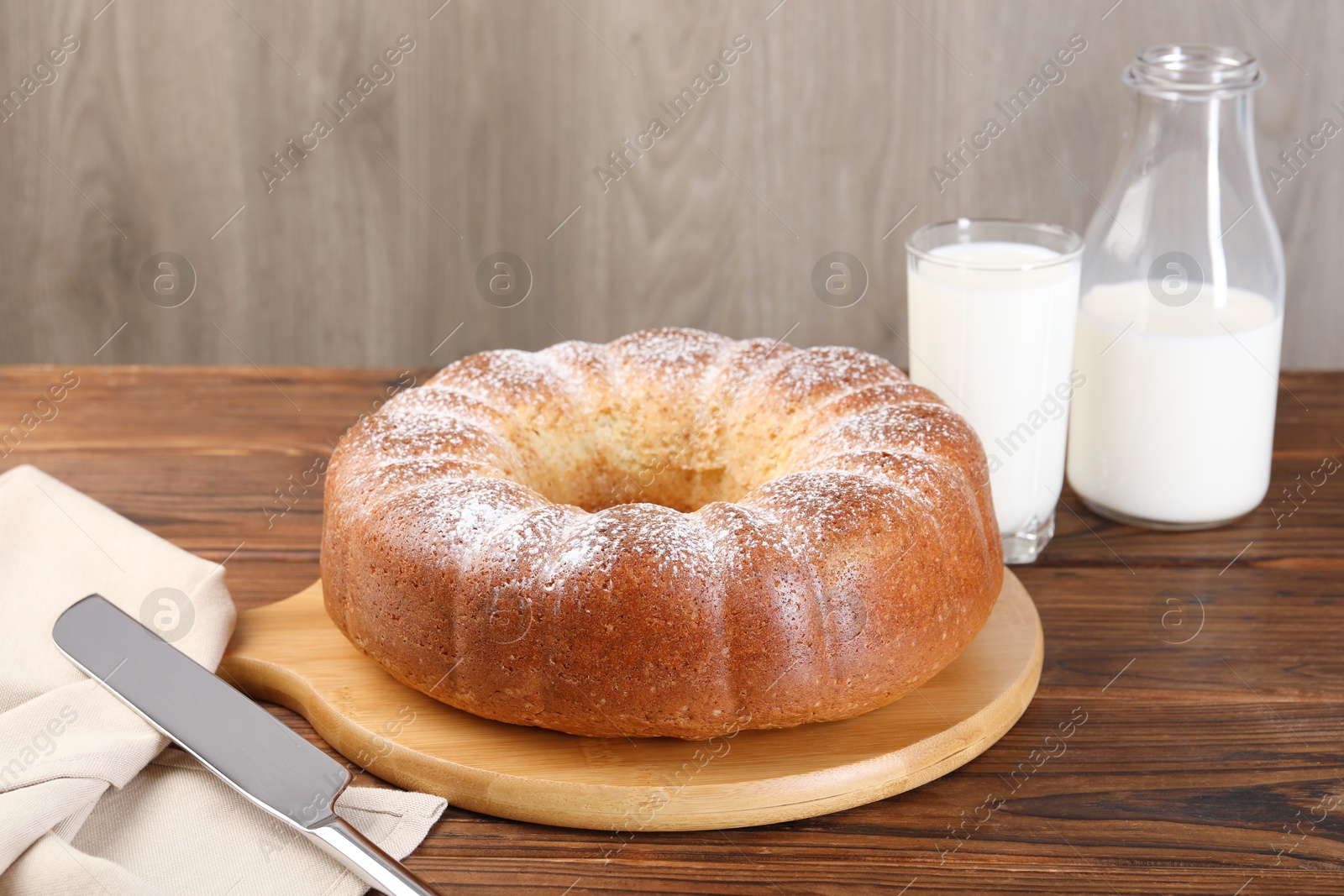 Photo of Freshly baked sponge cake, knife and milk on wooden table