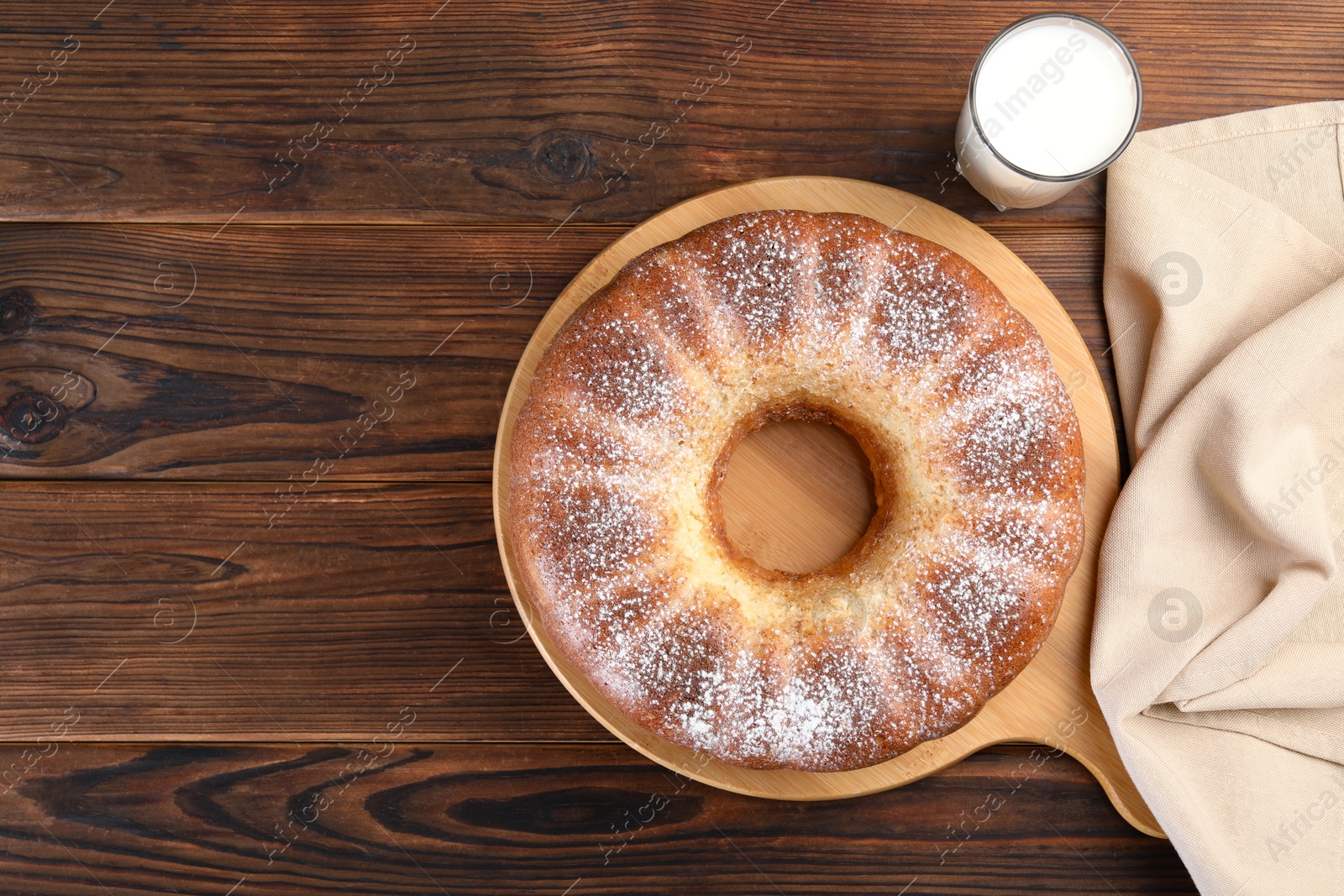 Photo of Freshly baked sponge cake and milk on wooden table, top view. Space for text