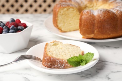 Photo of Freshly baked sponge cake, mint and berries on white marble table, closeup