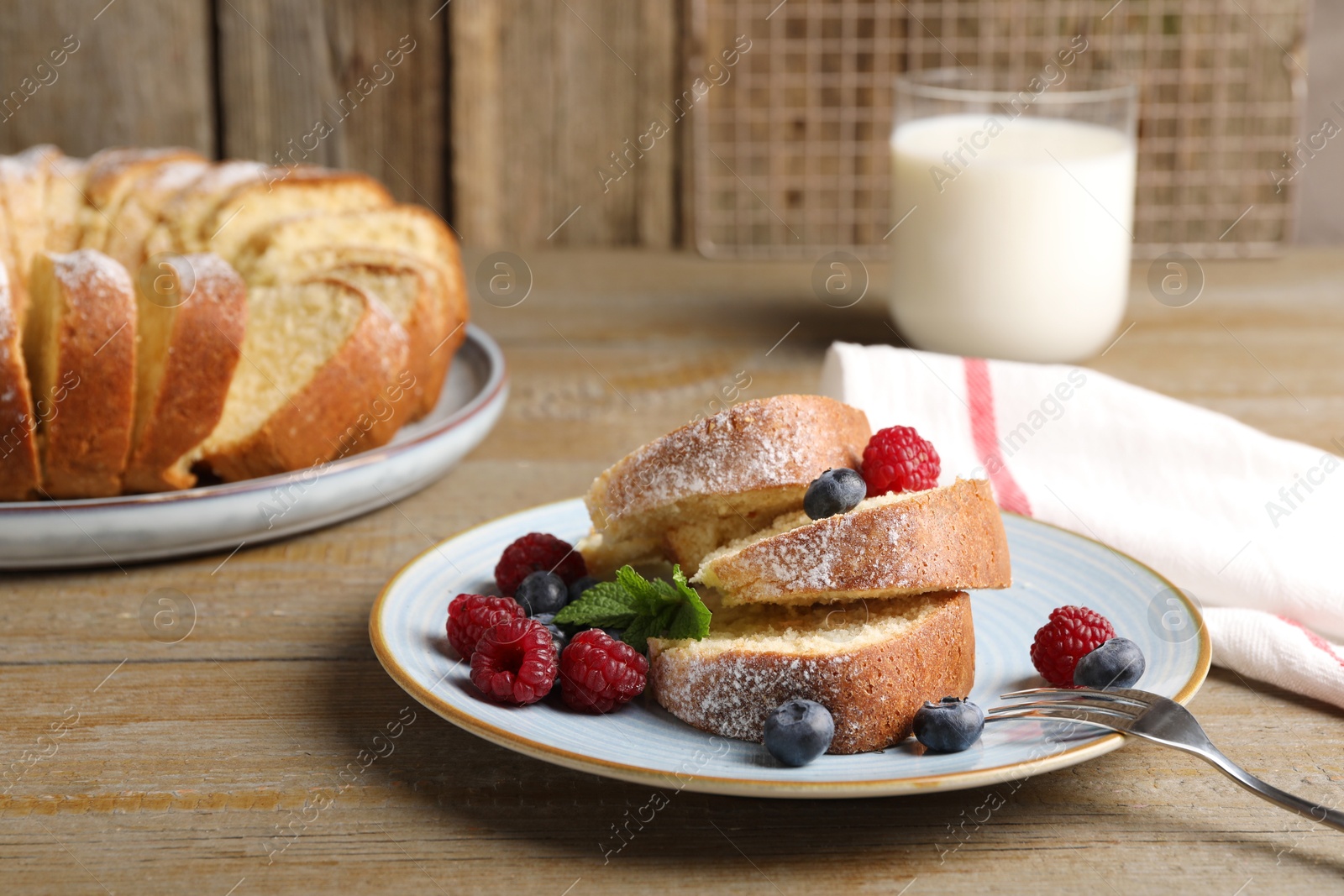 Photo of Pieces of freshly baked sponge cake, berries and milk on wooden table