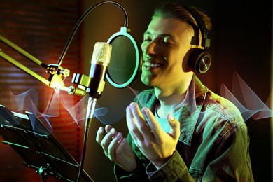 Image of Vocalist with headphones singing into microphone in professional record studio. Sound waves