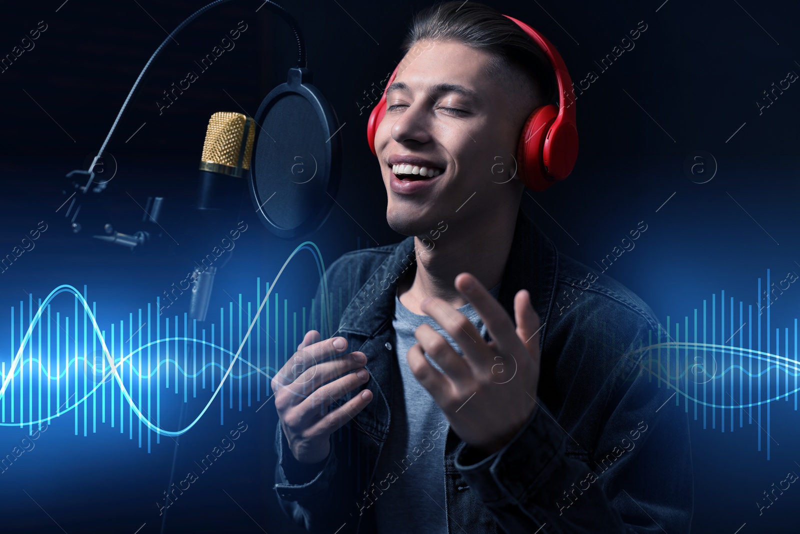 Image of Man with headphones singing into microphone in professional record studio. Sound waves