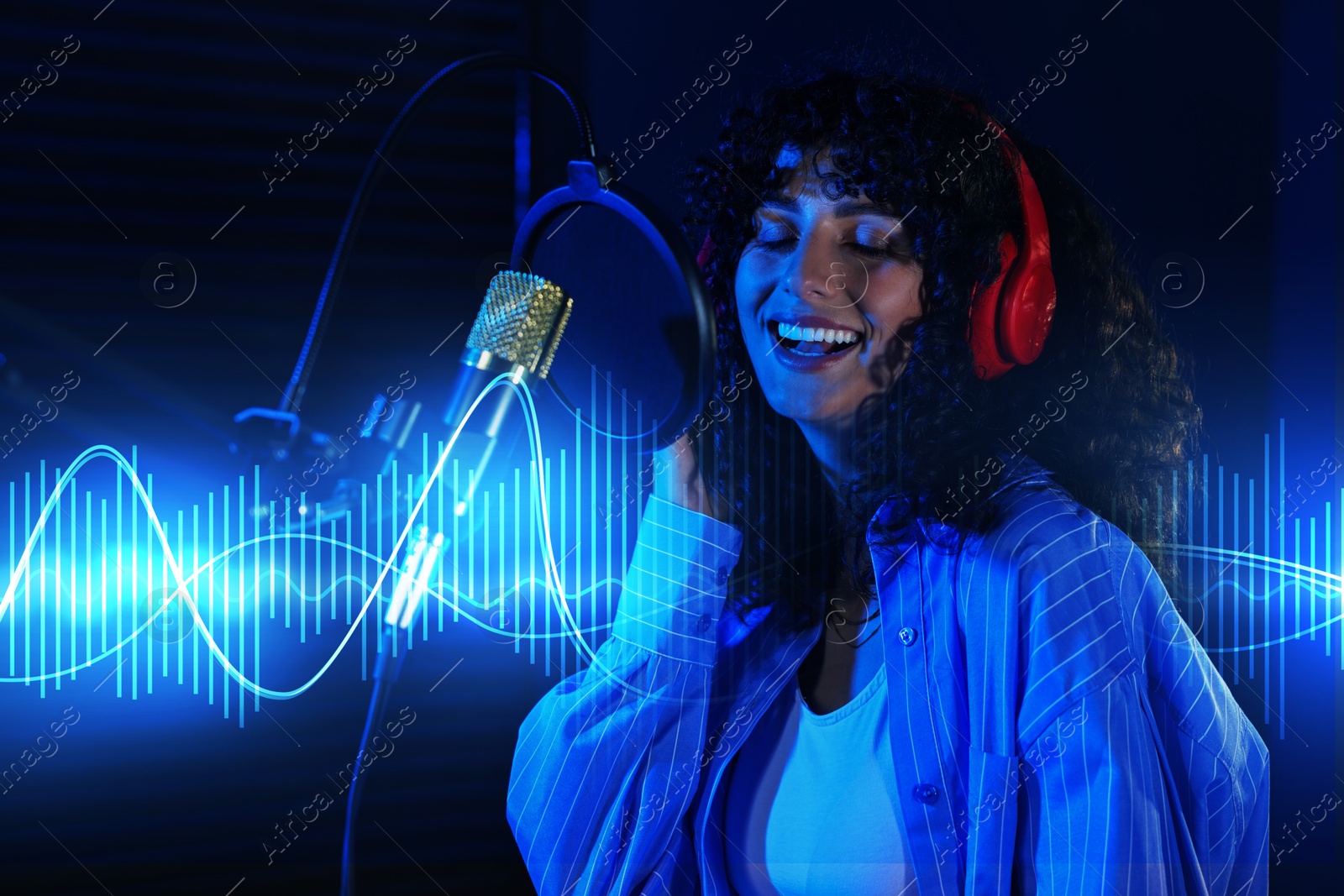 Image of Vocalist singing into microphone in professional record studio. Sound waves