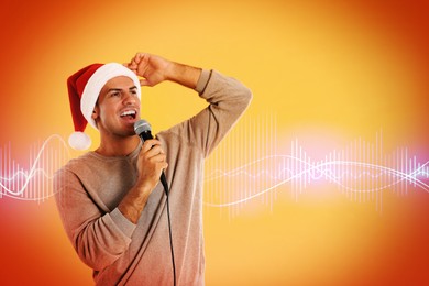 Man in Santa Claus hat singing with microphone on color background, space for text. Sound waves