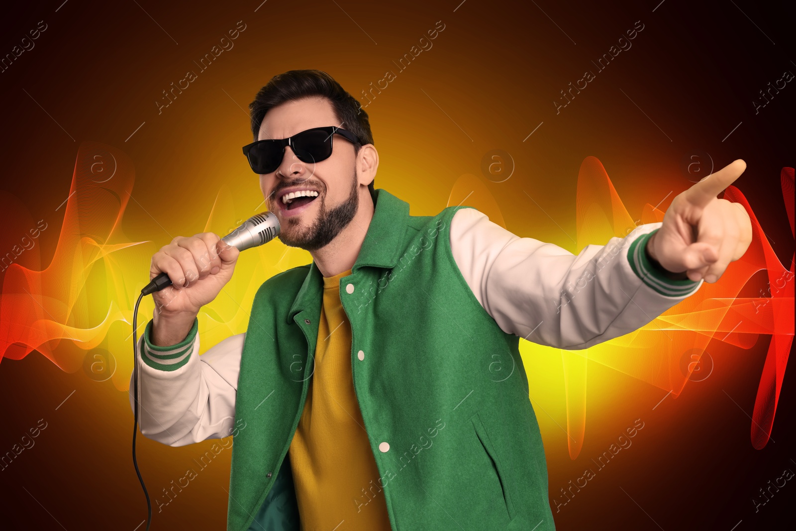 Image of Handsome man with sunglasses and microphone singing on color background. Sound waves