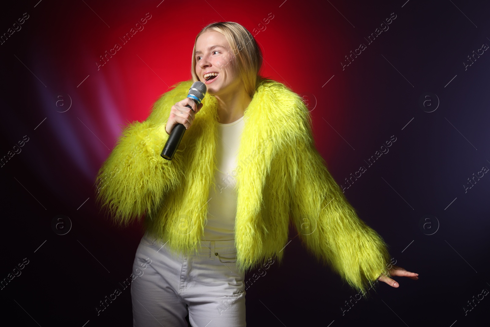 Photo of Talented singer in faux fur performing on dark background with red light