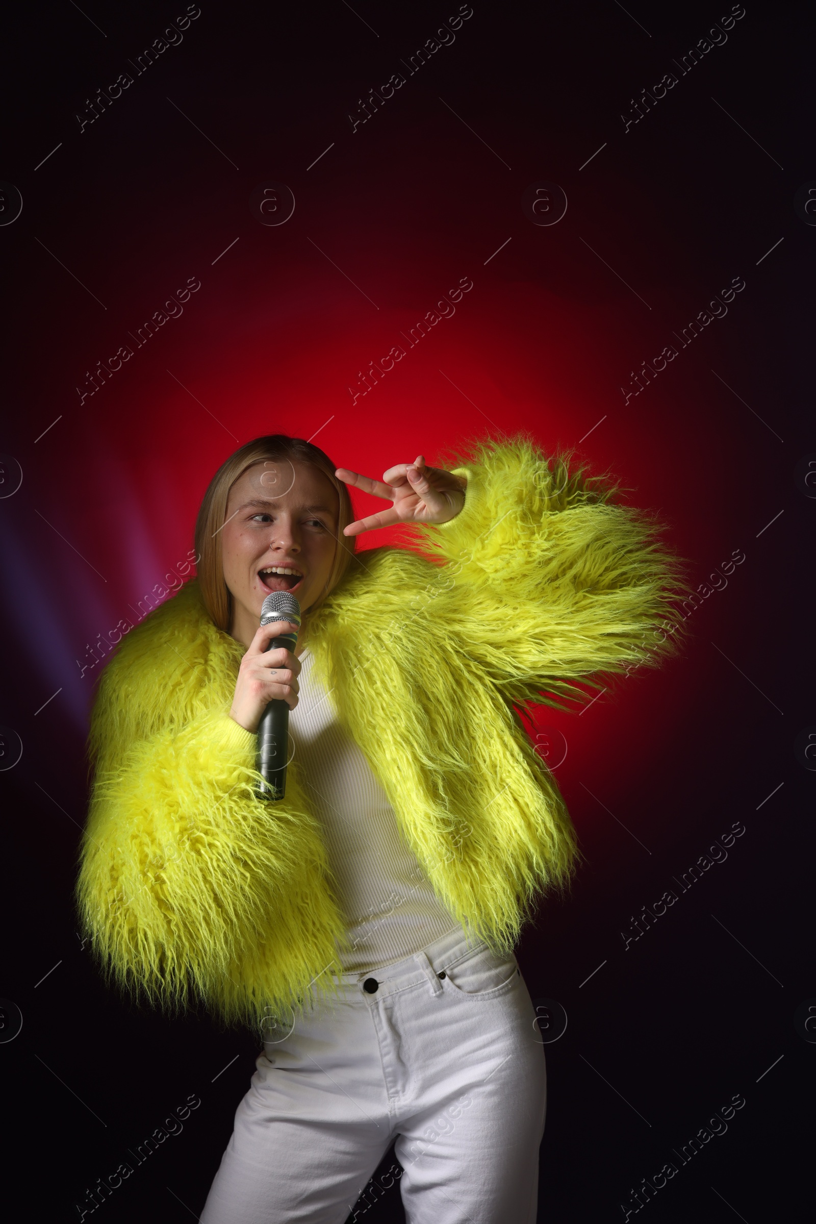 Photo of Talented singer in faux fur performing on dark background with red light