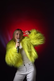 Talented singer in faux fur performing on dark background with red light