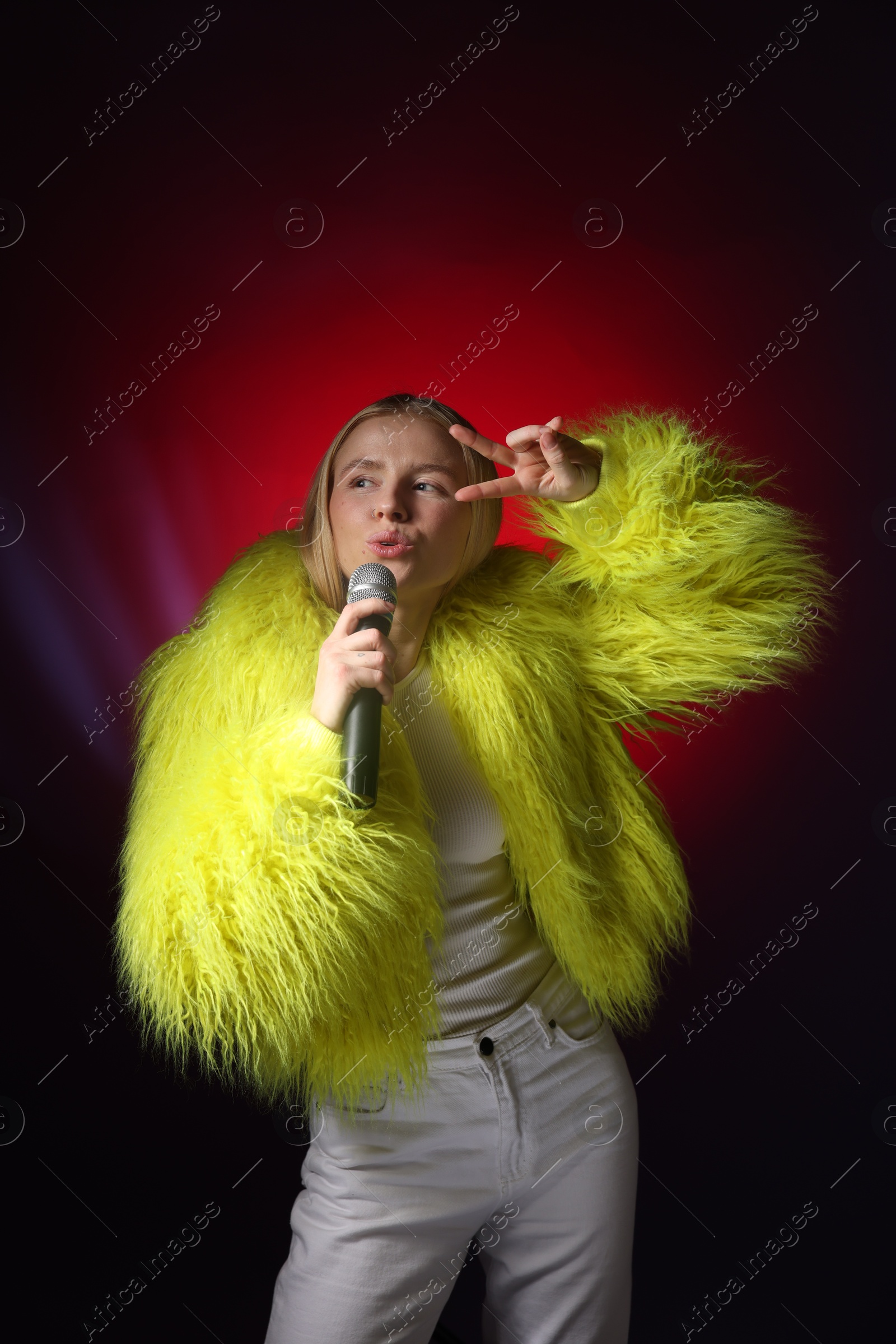 Photo of Talented singer in faux fur performing on dark background with red light