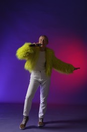 Photo of Talented singer in faux fur performing on purple background with pink light