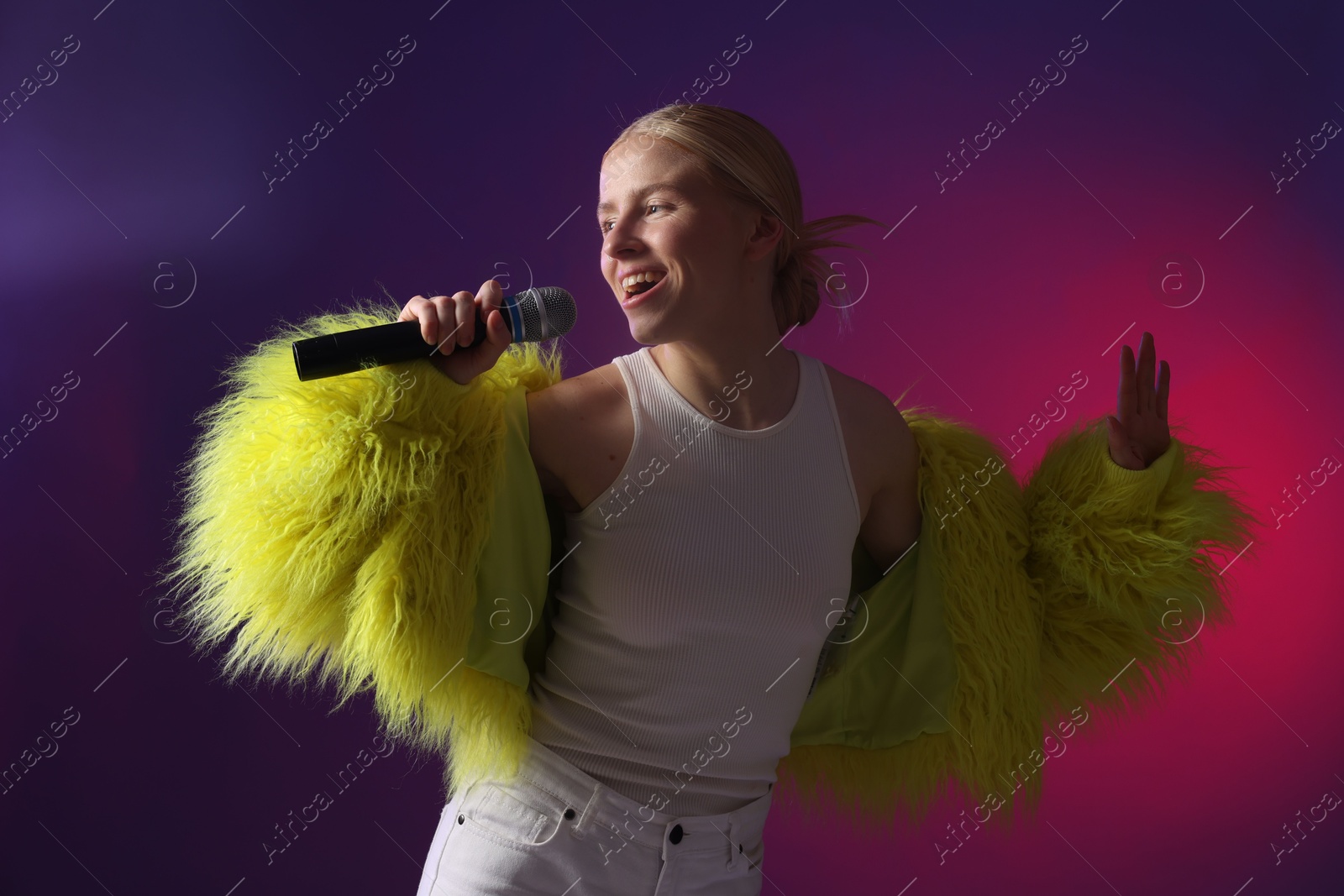 Photo of Talented singer in faux fur performing on purple background with pink light