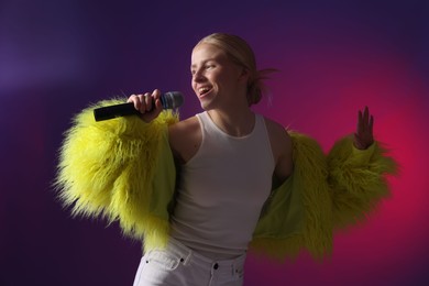 Photo of Talented singer in faux fur performing on purple background with pink light