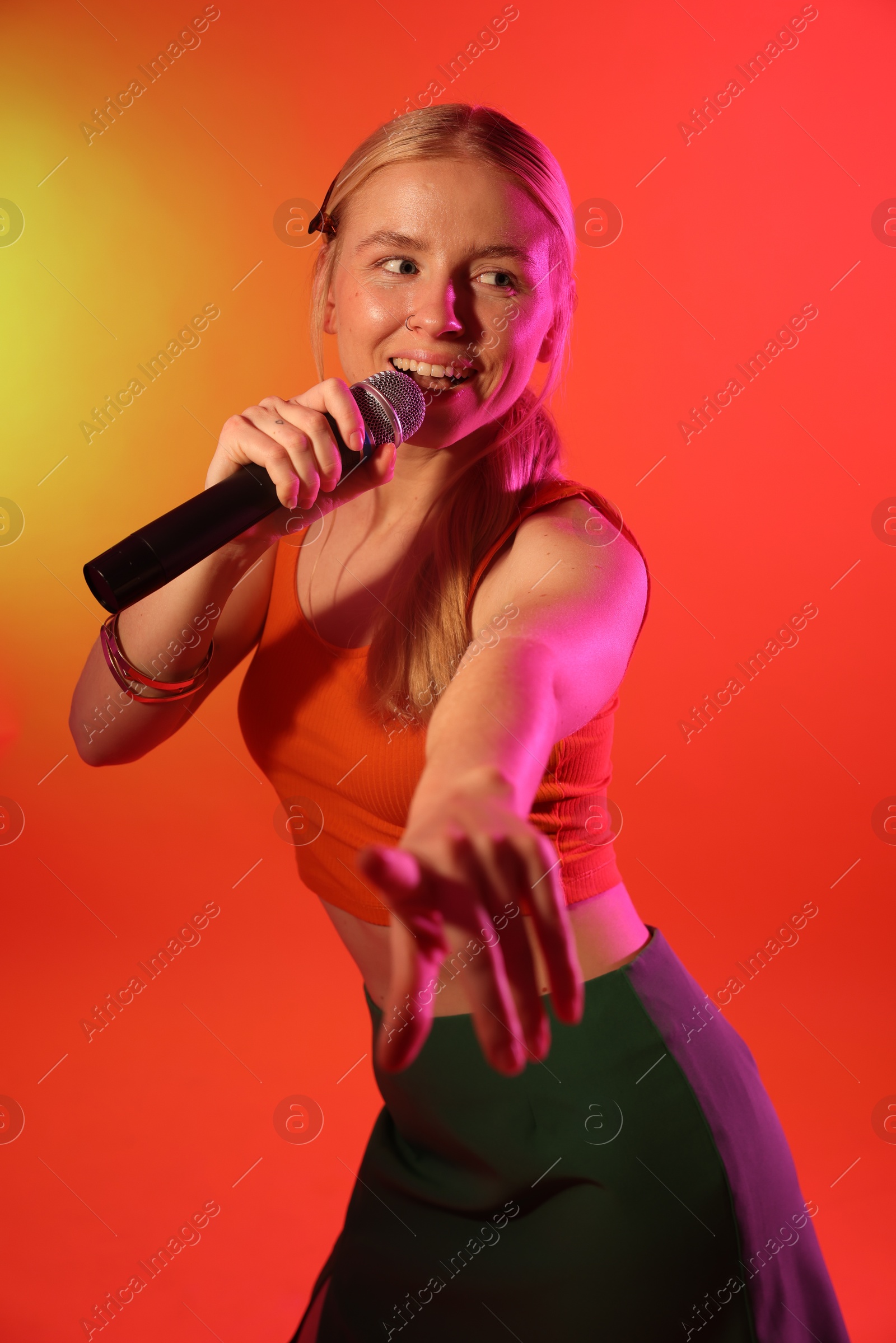 Photo of Talented singer performing on red background with yellow light