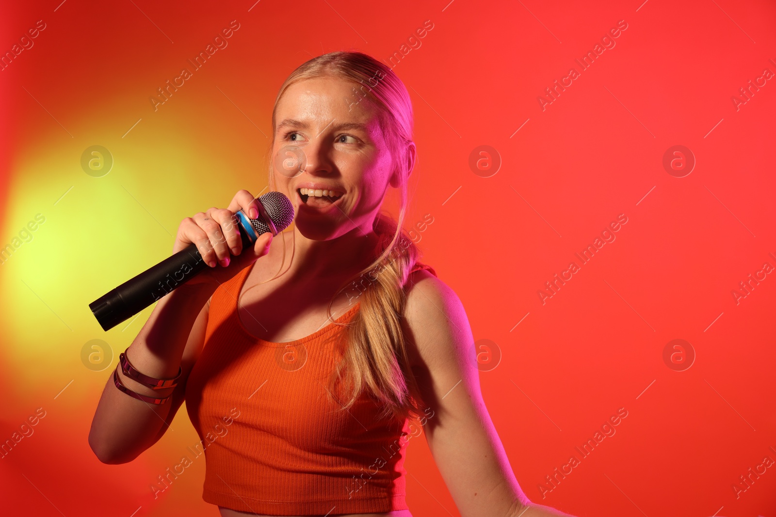 Photo of Talented singer performing on red background with yellow light