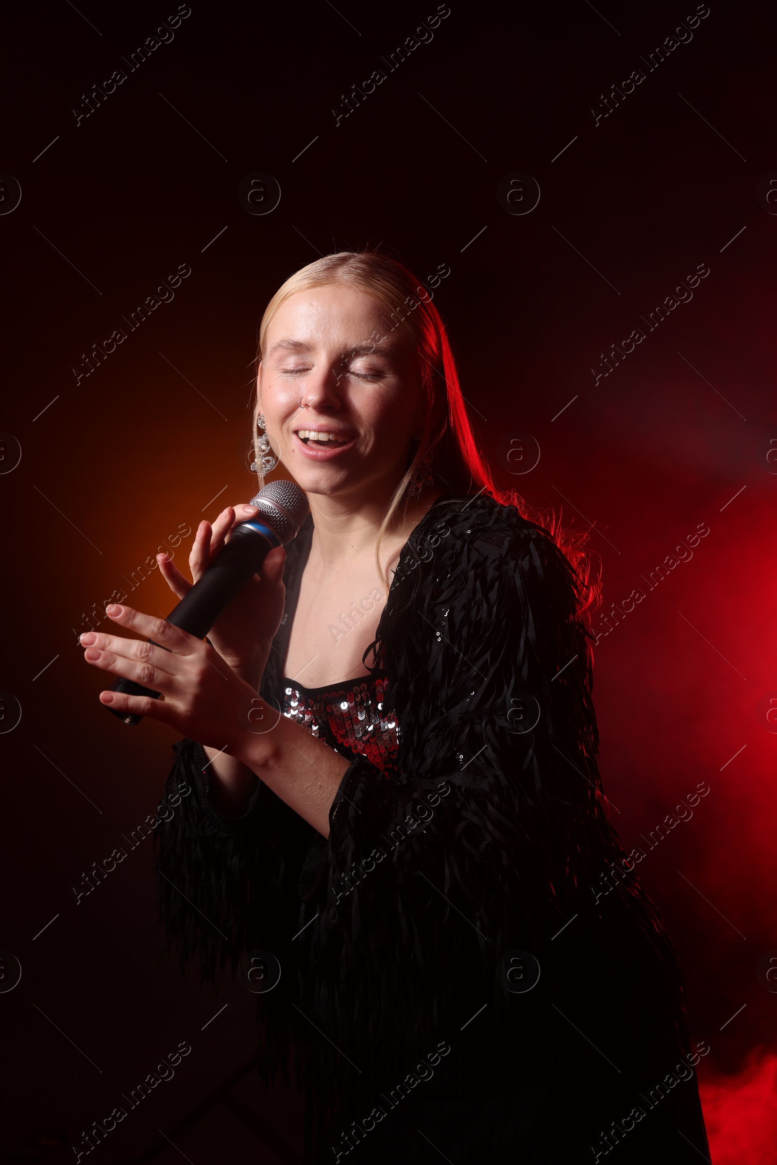 Photo of Beautiful singer performing on dark background with orange light