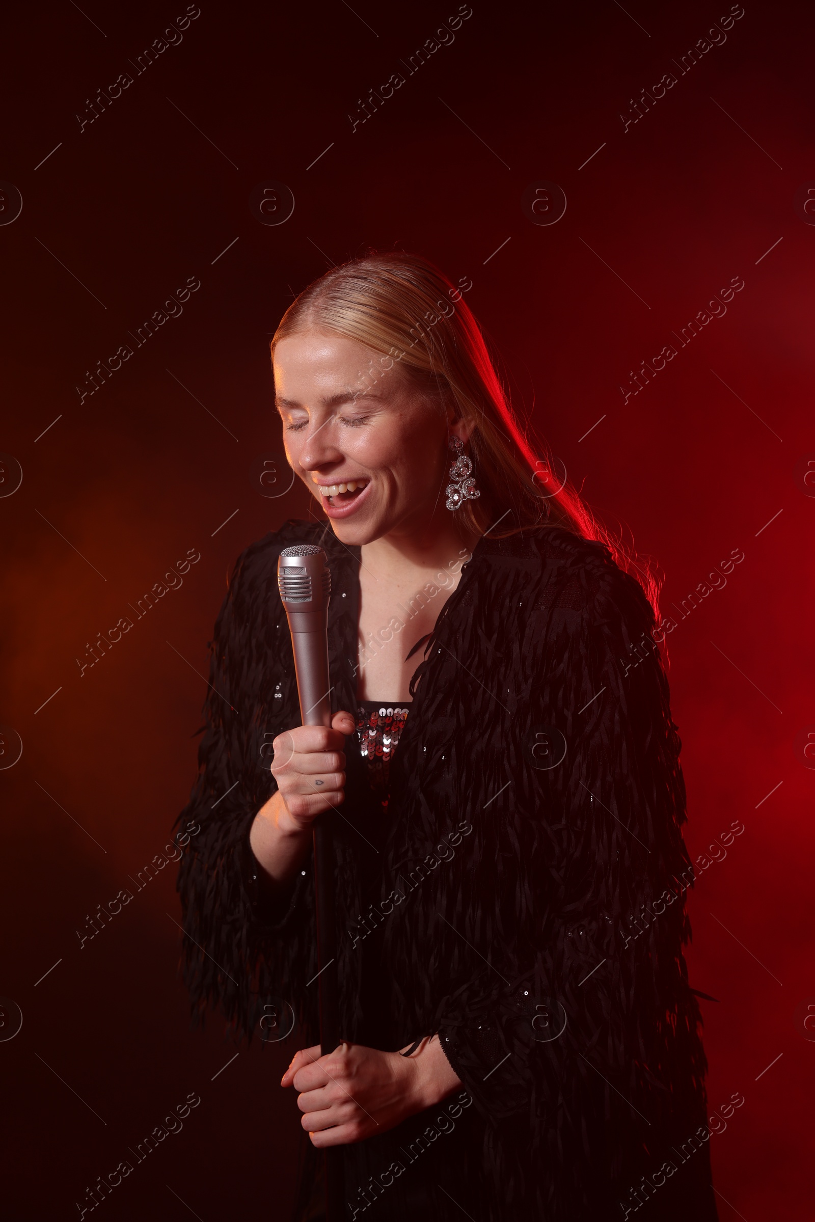 Photo of Beautiful singer performing on dark background with red light