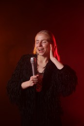 Beautiful singer performing on dark background with red light