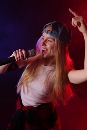 Talented singer performing on dark background with color lights