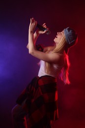 Photo of Talented singer performing on dark background with color lights