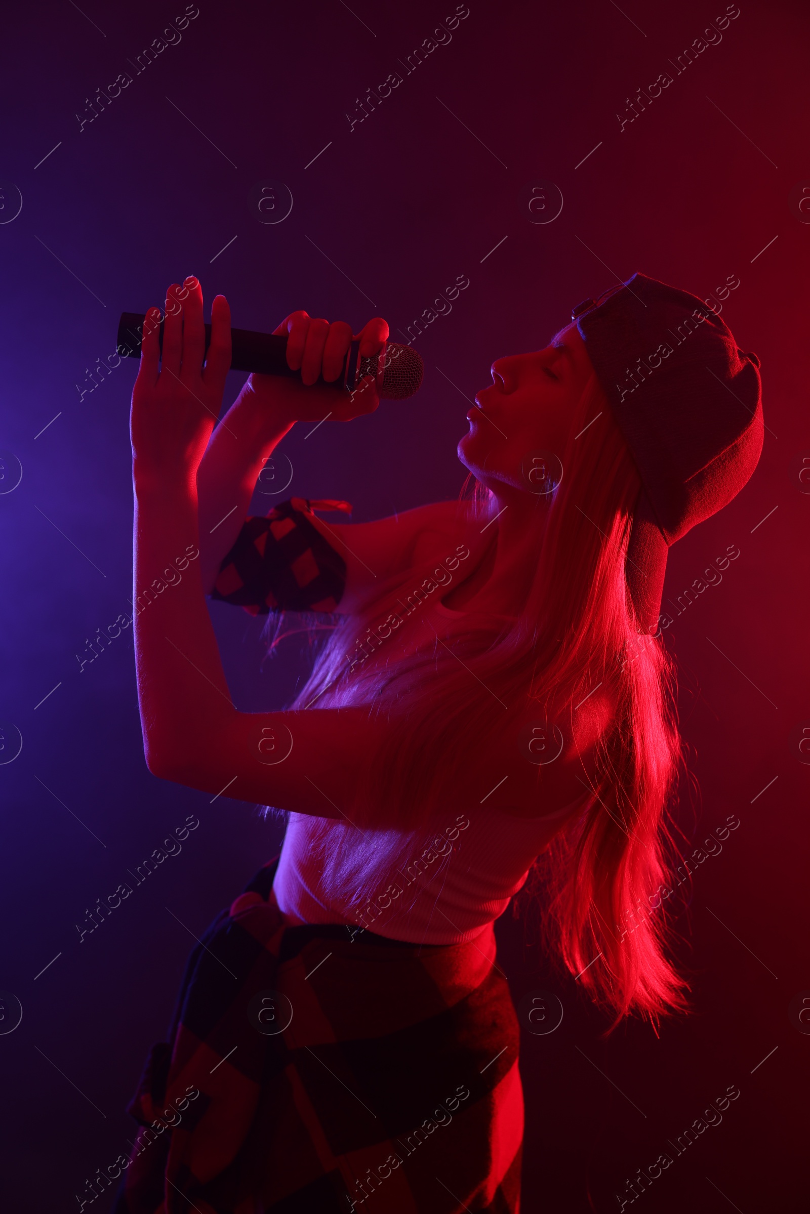 Photo of Talented singer performing on dark background with color lights