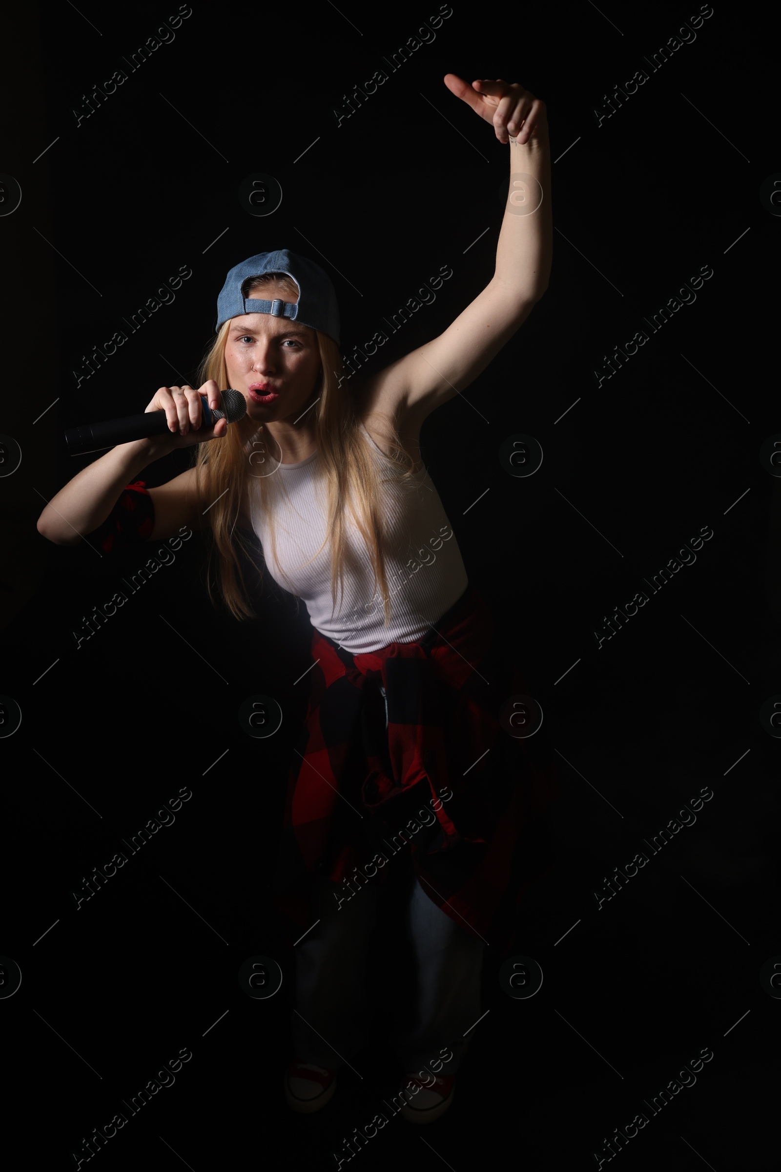 Photo of Talented singer with microphone performing on black background