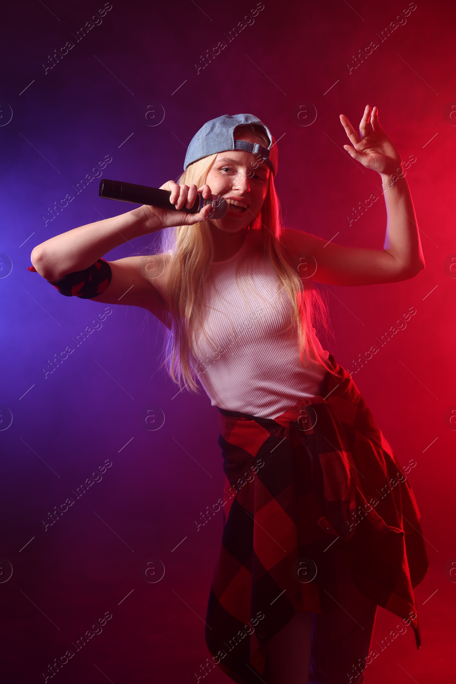 Photo of Talented singer performing on dark background with color lights